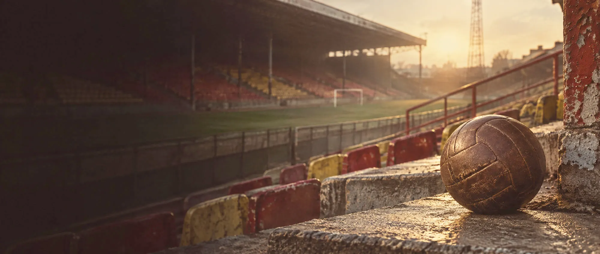 Old stadium terrace at golden hour with a vintage leather football on the steps